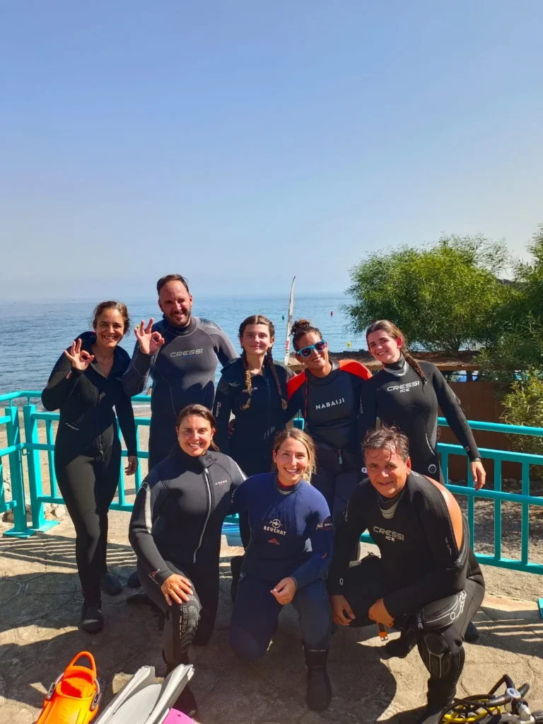 Grupo de buceadores con neopreno junto a la costa